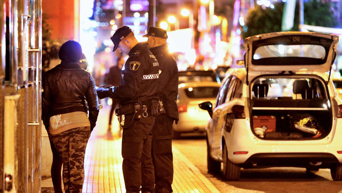 Polizisten kontrollieren zwei Frauen nachts auf der Straße.