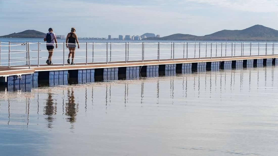 Zwei Menschen gehen über einen Steg über dem Mar Menor.