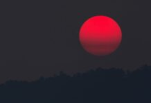 What causes the Sun to appear red when there are fires?