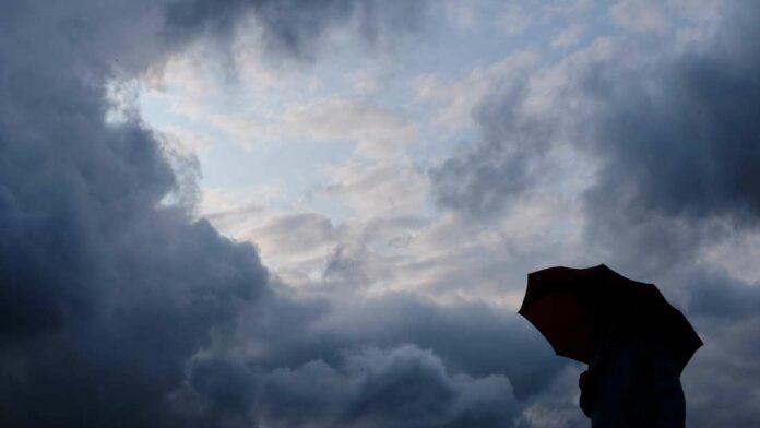 29609396-ein-mann-geht-mit-regenschirm-vor-aufziehenden-wolken-spazieren-3zfe